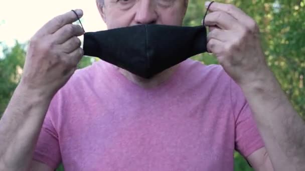 Senior man met medisch masker poserend in het zonnige park. — Stockvideo