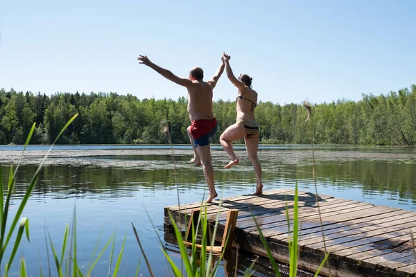 Muž a žena skok k jezeru vody spolu baví — Stock fotografie