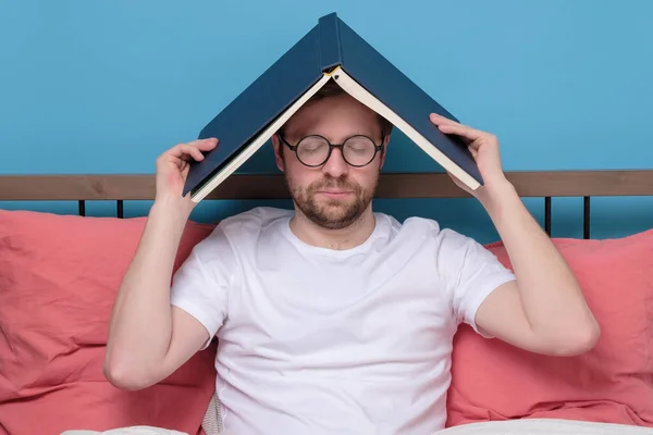 Задумчивый студент читает книгу в постели усталый — стоковое фото