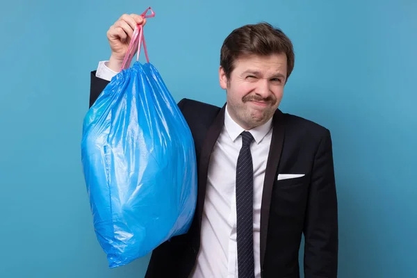 Homem de terno segurando saco de lixo azul — Fotografia de Stock