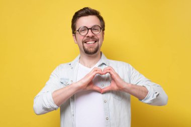 Genç beyaz adam kalp hareketi yapıyor.