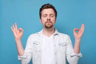 Yakışıklı adam elini kaldırarak meditasyon yapıyor ve Zen hareketi yapıyor, rahatlıyor.