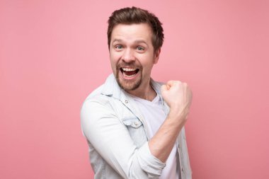 Genç beyaz adam heyecanını ve zevkini yumruğunu sıkarak ifade ediyor.