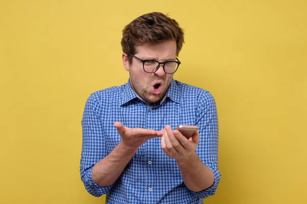 Wściekły człowiek z telefonem w ręku czytający smsy — Zdjęcie stockowe