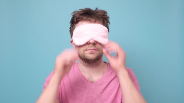 Schläfriger Mann nimmt Schlafmaske ab und blickt überrascht in Kamera. — Stockvideo