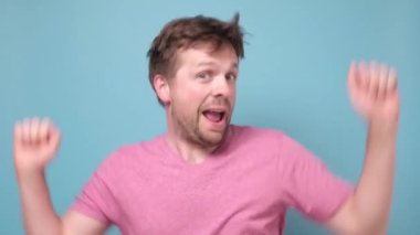 Neşeli beyaz adam mavi arka planda dans ediyor..