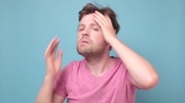 Komik adam saçını düzleştiriyor, kameraya bakıyor ve gülümsüyor.