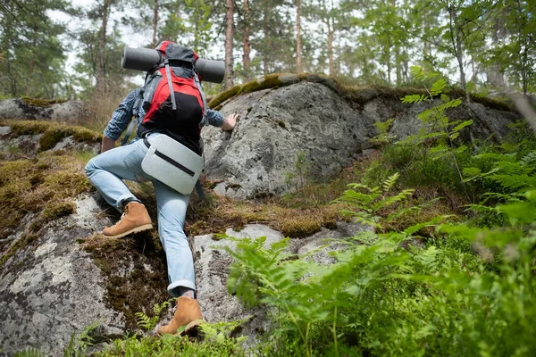 Mann mit Rucksack klettert beim Wandern im Wald auf. — Stockfoto