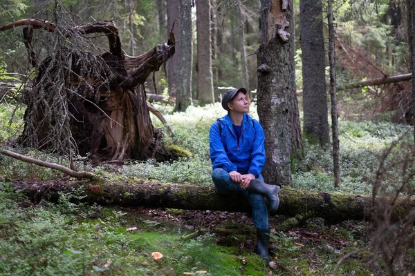 Путешественник, сидящий на упавшем дереве в лесу. — стоковое фото