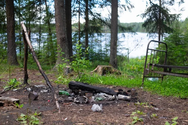 Lixo e lareira na floresta perto do lago . — Fotografia de Stock