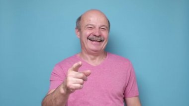 Kıdemli İspanyol adam sana gülüyor, kamerayı işaret ediyor.