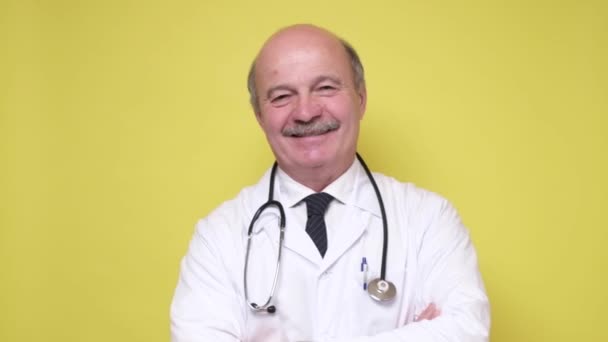 Doctor en bata de laboratorio y estetoscopio sonriendo mirando a la cámara — Vídeo de stock