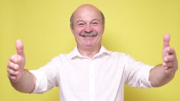 Senior uomo maturo dare a qualcuno un abbraccio, isolato sfondo giallo. — Video Stock