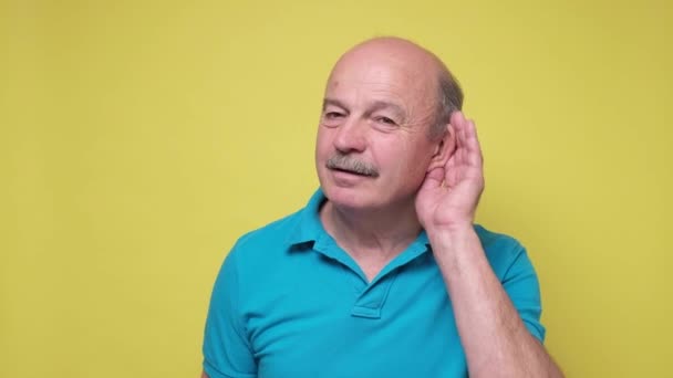 Hombre mayor tratando de escuchar las últimas noticias cogido de la mano cerca de la oreja — Vídeo de stock