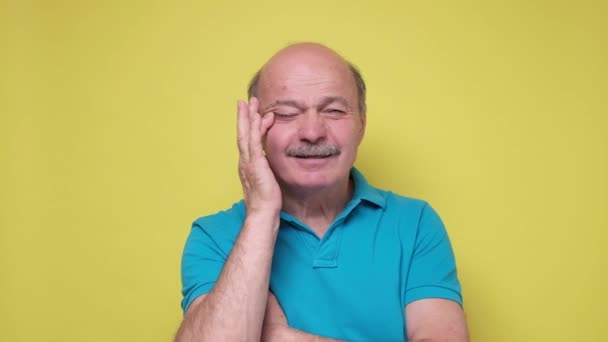 Старший кавказский человек в синем косоглазым пытается увидеть маленький текст. — стоковое видео