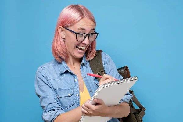 Menina estudante engraçado com óculos escrevendo no bloco de notas — Fotografia de Stock