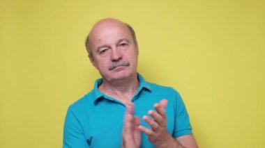 Mavi gömlekli kıdemli İspanyol adam alkışlıyor.