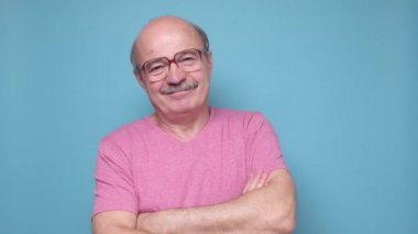 Yakışıklı son sınıf öğrencisi kollarını kavuşturup gülümsüyor.