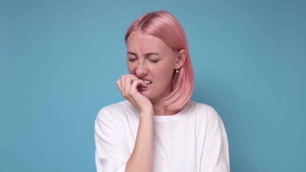Blanke jonge vrouw met roze geverfd haar bijt nagels gevoel nerveus — Stockvideo