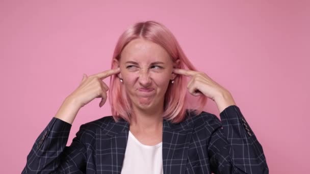 Ung vacker kaukasiska kvinna täcker öronen med fingrar med irriterad uttryck — Stockvideo