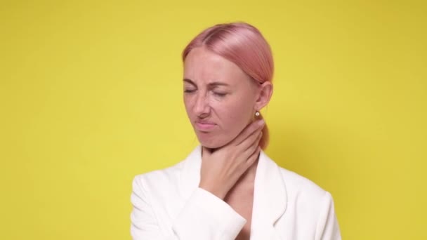 Hezká žena trpí bolestí v krku na žlutém pozadí — Stock video