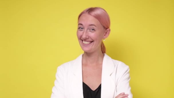 Gyönyörű fiatal lány boldogan egyetért a kamera felett sárga háttér — Stock videók