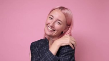 Rahatlamış, mutlu, genç bir kadın, neşeli bir yüz ifadesi takınarak kendine sarılıyor.