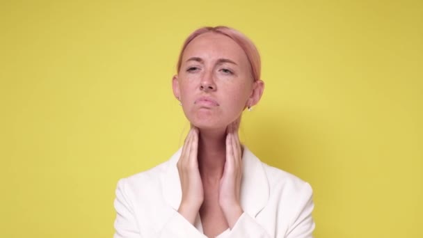 Junge Kaukasierin überprüft Schilddrüse auf gelbem Hintergrund — Stockvideo