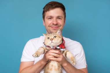 İngiliz tekir kedisi olan genç adam mavi arka planda izole edilmiş..