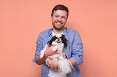 Mutlu beyaz adam, sevimli köpekleri tutuyor ve rahatlatıyor. Japon çenesi.