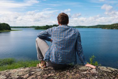 Bir tepede oturan adam gölün suyuna bakıyor..
