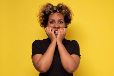 Güzel, genç Afrikalı bir kadın tırnaklarını yiyor, korkuyor ya da gergin.