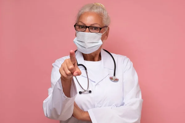 Donna anziana con stetoscopio con indosso maschera medico che ti indica. — Foto Stock