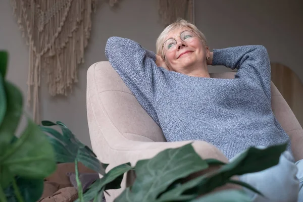 Europeisk kvinna vilar, glad över goda nyheter, sitter hemma på soffan — Stockfoto