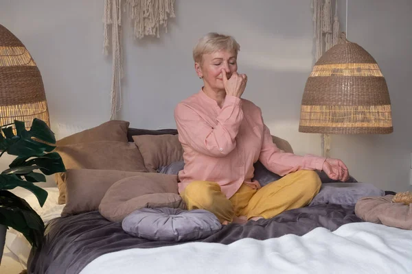 Senior woman practicing yoga at home, making Alternate Nostril Breathing exercise, nadi shodhana pranayama — Stock Photo, Image