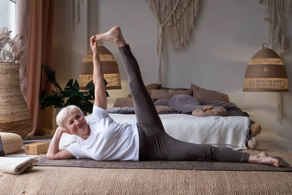 Woman doing fitness workout, exercise stretching legs, Anantasana or Side Reclining Leg Lift yoga pos — Stock Photo, Image