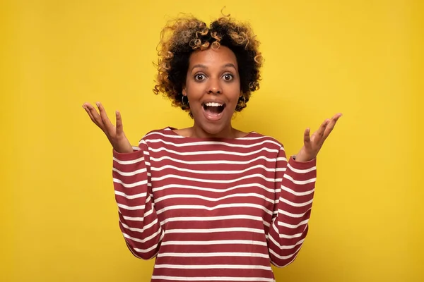 Mulher africana feliz de ver grandes descontos em roupas, expressa choque, mantém as mãos perto da cabeça. — Fotografia de Stock