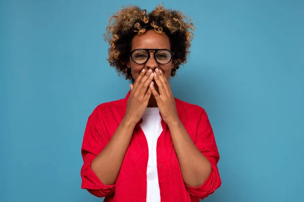 Mulher afro-americana com cabelo encaracolado rindo e riso embaraçado cobrindo boca com as mãos — Fotografia de Stock