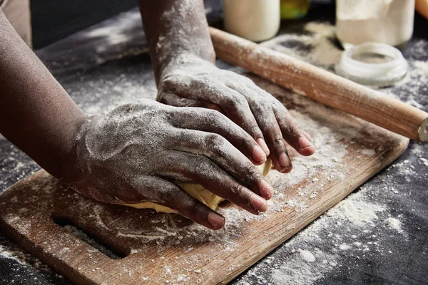 Cropped shot of male`s hands knead dough for preparing roll or pizza, works with rolling pin, uses flour and other ingredients to make pastry soft. Talented cook shows master class of baking cake