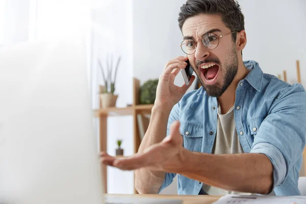 Mad executive manager has quarrel with employee over cell phone, dissatisfied with bad report and failure. Irritated furious male angry with software bugs in application, can`t continue work