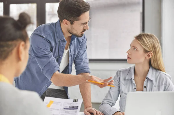 Portrait of skilled talented male executive director gives tasks for working day to his female employees, asks to prepare business report. Successful freelancers create new marketing strategy