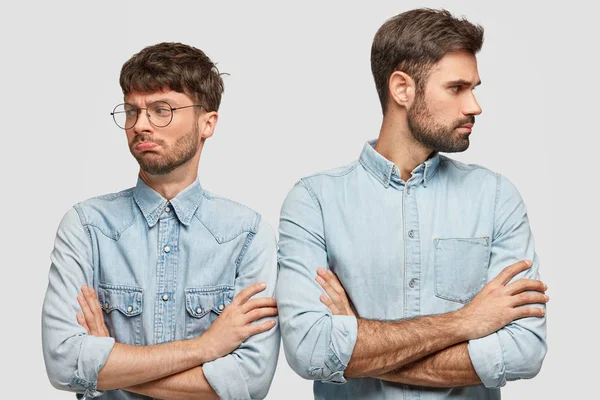 Two brothers can`t share inherit house, keeps arms folded, don`t look at each other, have argue, curve lips, have displeased expressions, express disagreement, isolated over white background