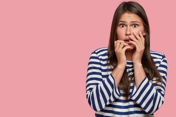 What if someone will know my secret. Nervous embarrassed girlfriend looks with frightened expression, afraid of revealing her betrayal, terrified to death, poses over pink background with free space