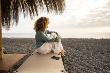 güzel beyaz insanlar plajda çıplak ayak ve bekleyen güzel bir elbise ile koltuk üzerinde aşağı oturup model. arkadaş grubu bağlı kalmak ve Internet e-posta kontrol etmek için cep telefonu.