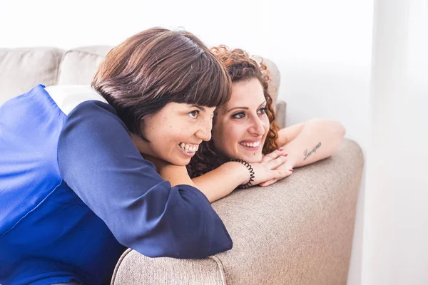 güzel zaman ve mutluluk ile gülmek ve iki beyaz arkadaş için gülümsüyor beraber evde kanepede yat. dostluk kavramı için kapalı resim pencere doğal ışık ile