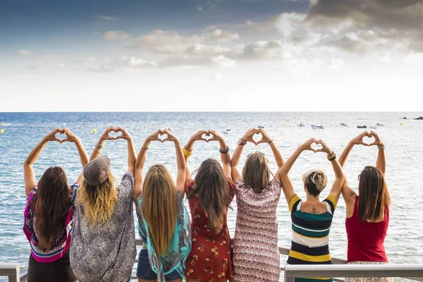 美丽的七女孩从背后做一颗心 双手望着大海等待夕阳的假期休闲活动 友谊永远在一起概念 旅行到海地方 — 图库照片