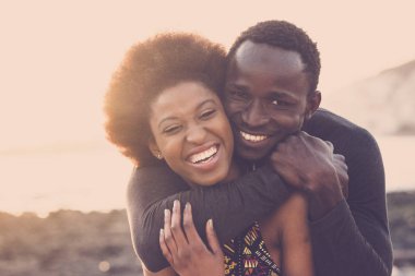 güzel siyah ırk güzel modeli çift erkek ve kadın genç yaşta sarılmak ve konaklama ile birlikte sevgi ve dostluk. tatil veya yaşam tarzı için plaja yakın açık manzaralı yer.