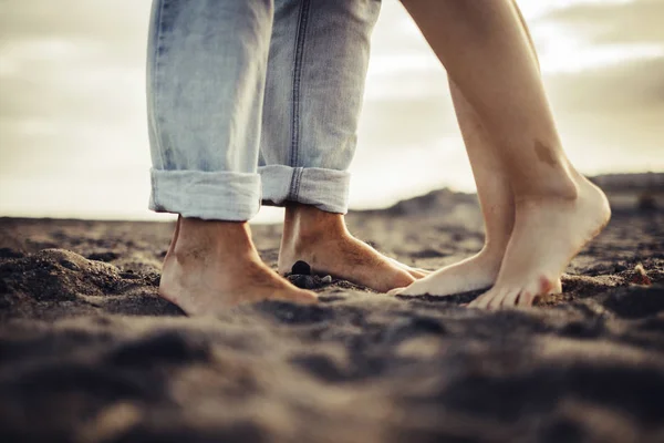 true and real love forever together concept with two pair of feet man and woman caucasian stay close probably for a kiss. sexy and naked body part. sand and beach place and sunset background