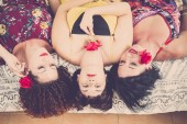 szép és gyönyörű három kaukázusi nők otthon. feküdt az ágyra keresnek fel a nagy mosoly és a boldogság. játszik a rózsa és a piros színű rúzs és a virágok. boldogság barátság koncepció kép