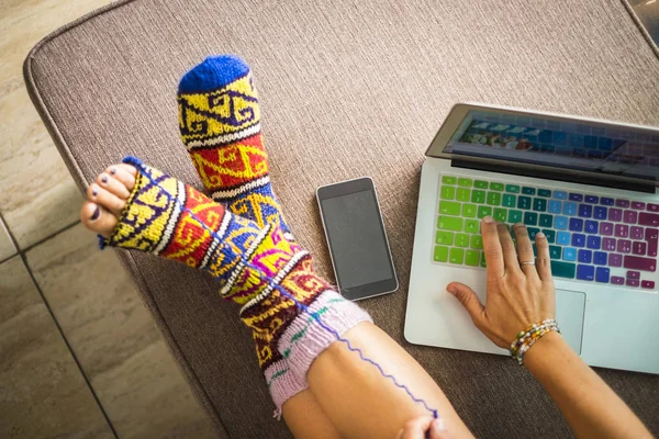 colorful home scene with caucasian woman legs with funny colored socks with hole that the feet come out. work on a tablet with colors keyboard. artist writer and worker at home concept for freedom female